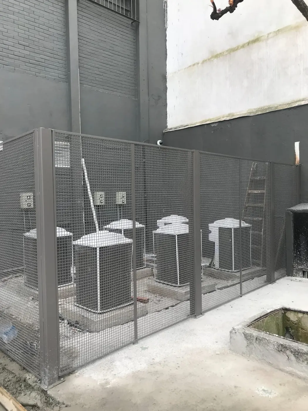 Grade de tela metálica cercando os aparelhos de ar-condicionado